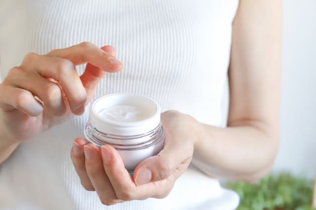 美容クリームに手を伸ばす女性